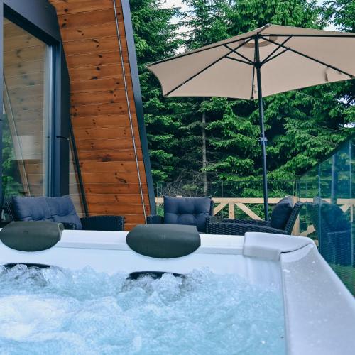 a hot tub with chairs and an umbrella at Tara mountain house Kopaonik in Kopaonik