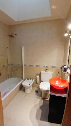 a bathroom with a red sink and a toilet and a tub at Temporario balcarce in Santo Tomé