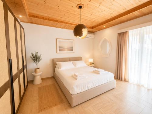 a bedroom with a white bed and a wooden ceiling at Portside Living in Sarandë