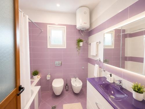 a purple bathroom with a toilet and a sink at Portside Living in Sarandë