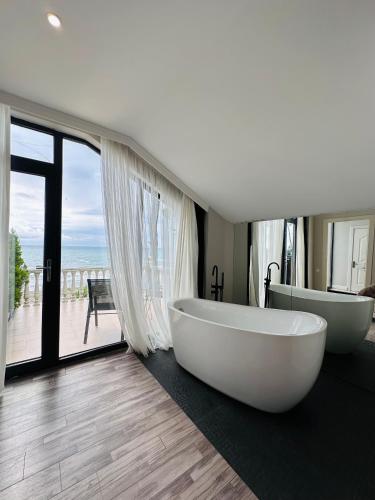 a bathroom with two white tubs and a large window at Villa Marnero in Grigoleti