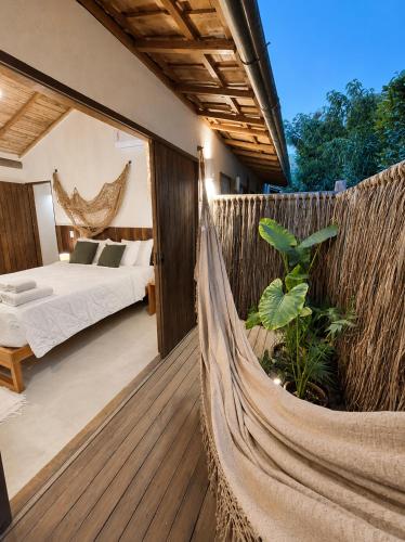 a hammock in a room with a bed and a bedroom at Pousada Vila Verde Vila de Caraíva in Caraíva