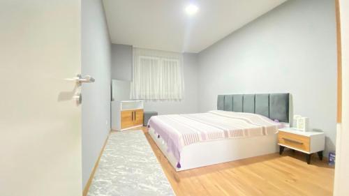 a white bedroom with a bed and a window at Fiona's apartment in Gjakove