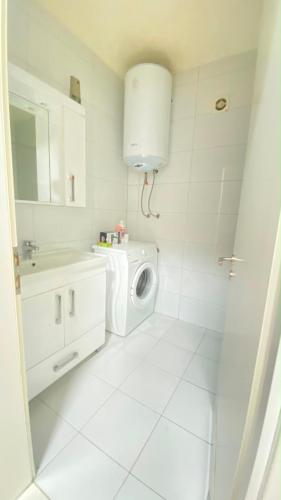 a white bathroom with a washing machine and a sink at Fiona's apartment in Gjakove