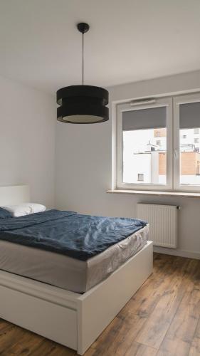 a bedroom with a bed and a lamp and two windows at BEMO Apartment in Warsaw