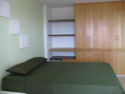 a bedroom with a green bed and wooden cabinets at Victory Flat Intermares in Cabedelo