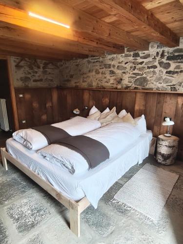a large bed in a room with a stone wall at Rifugio in Voga in Gordona