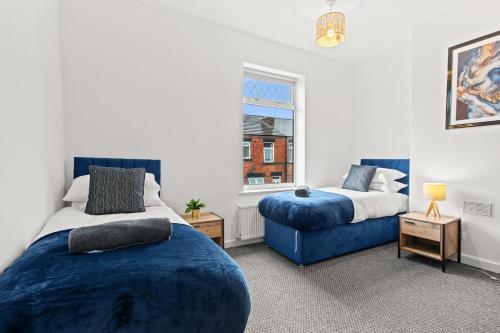 a bedroom with two beds and a blue couch at Haydock Contractor House, 2-Bed, Easy M6 Access in Haydock