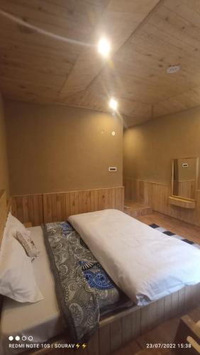 a large bed in a room with a wooden ceiling at Tirthan river edge in Bathād