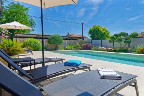 a pool with chairs and an umbrella next to a swimming pool at Villa Morgan by Rent Istria in Umag