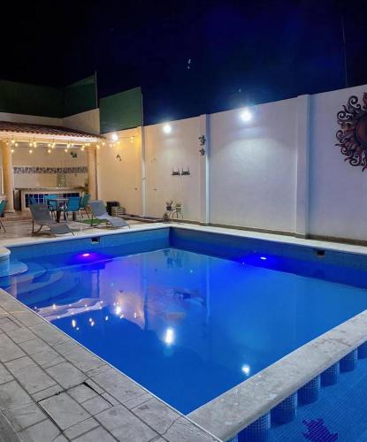 a large swimming pool with blue water at night at HOTEL LAS FUENTES in Tepotzotlán