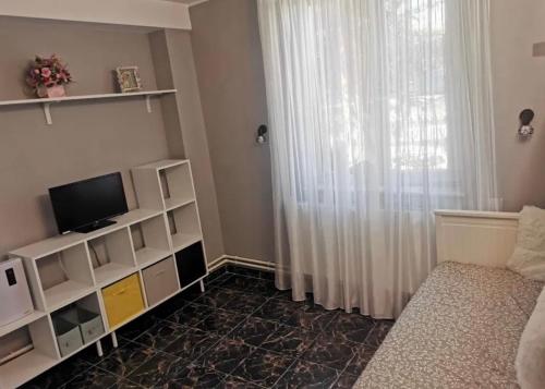 a living room with a television and a window at Saturn Cozy Stay in Mangalia