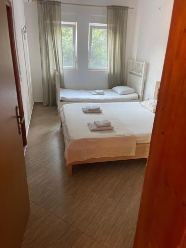 a bedroom with two beds and two windows at Apartmani Minna Alim in Utjeha