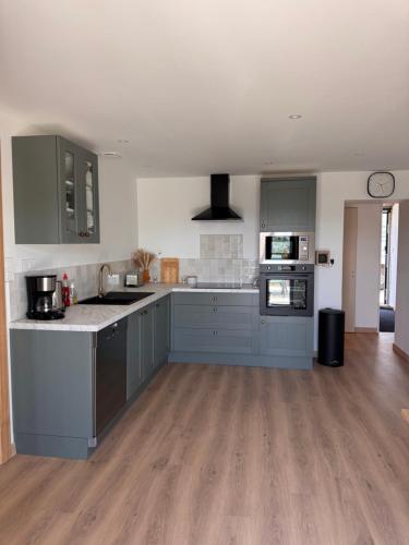 a large kitchen with blue cabinets and a wooden floor at Gîte la Tinou in Saint-Nabord