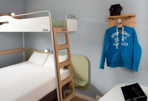a bunk bed with a ladder and a jacket on a wall at ibis budget Bergerac in Bergerac