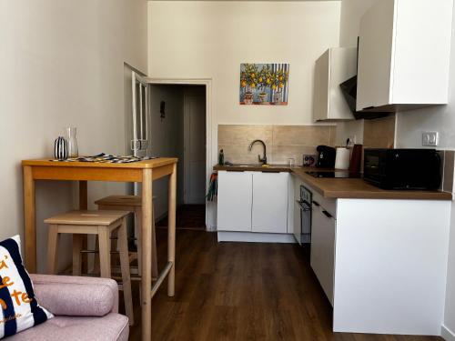 a small kitchen with white cabinets and a table at Échappée Méditerranéenne in Lectoure