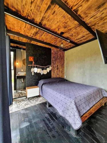 a purple bed in a room with a wooden ceiling at Cabañas Bosque Antiguo in Tapalpa