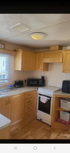 a kitchen with wooden cabinets and a white stove top oven at 1 The Willows Reighton Sands in Reighton