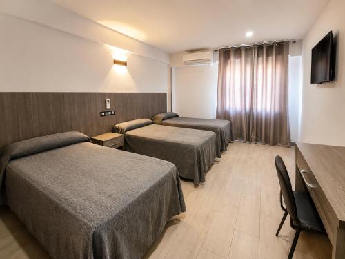 a hotel room with two beds and a television at Hostal Goyma I in San Fernando de Henares