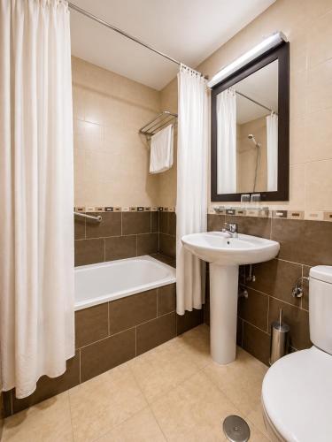 a bathroom with a sink and a tub and a toilet at Hostal Goyma I in San Fernando de Henares