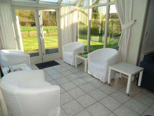 a room with white chairs and tables and windows at Bungalow in Breskens near Beach and Lighthouse in Breskens