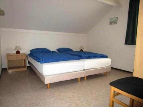 a bedroom with a large bed with blue sheets at Bungalow in Breskens near Beach and Pool in Breskens