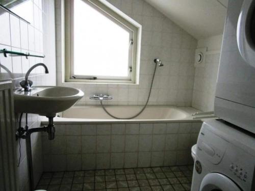 a bathroom with a sink and a tub and a window at Bungalow in Breskens near Beach and Pool in Breskens