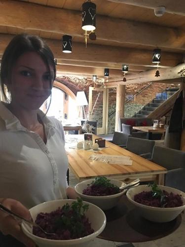 a woman holding two bowls of food in a restaurant at Piwnica Rycerska Kęty in Kęty