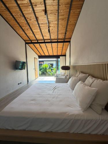 a bedroom with a large white bed with a wooden ceiling at CASALIA Sopetran in Sopetrán