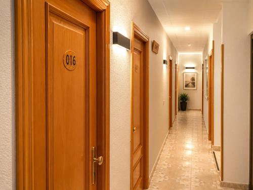 a hallway with wooden doors and a long corridor at Hostal Goyma II in San Fernando de Henares