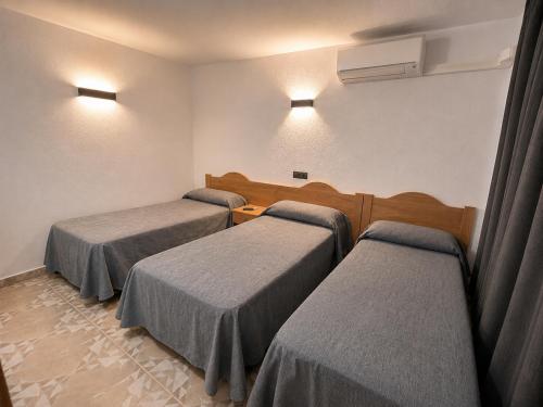a room with three beds in a room at Hostal Goyma II in San Fernando de Henares