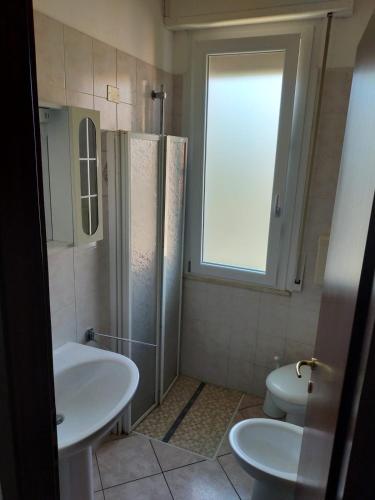 a bathroom with a sink and a toilet and a window at The sisters apartment in Punta Marina