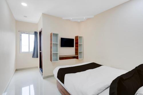 a white bedroom with a bed and a tv at Hotel O RB Delight in Karīmnagar