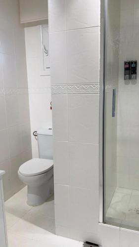a white bathroom with a toilet and a shower at Cabanas da Auga B in Casas Novas