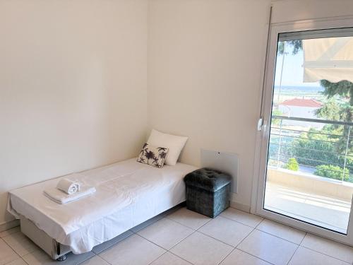 a small bed in a room with a window at Alexandros House in Néa Tríglia