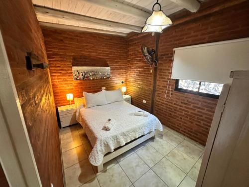 a bedroom with a bed and a brick wall at Casita siempre verde in Los Hornillos
