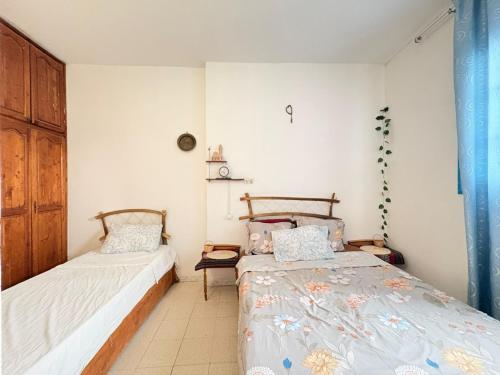 two beds in a room with white walls at Dar Essadeg in Tataouine