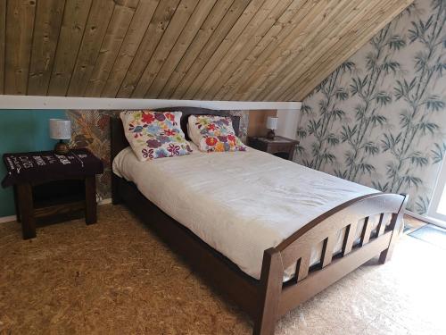 a bedroom with a large bed with a wooden ceiling at Les Marronniers Roses in Châteaulin