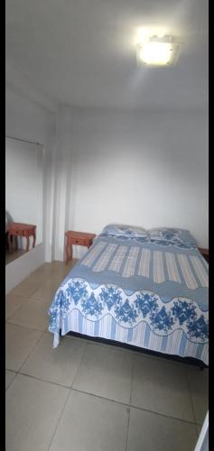 a bedroom with a bed with a blue and white comforter at COBERTURA Duplex 302,vista d Mar e piscina in Piúma
