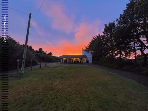 a building on a field with a sunset in the background at Tide Pool Cabin, a Soquinomere Private Hotel on the Dunes, Downtown Ocean Shores in Ocean Shores