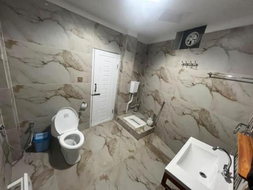 a bathroom with a white toilet and a sink at Ember Guest House in Abbottabad