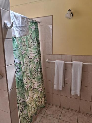 a shower curtain in a bathroom with towels at Playa Negra Guesthouse in Cahuita