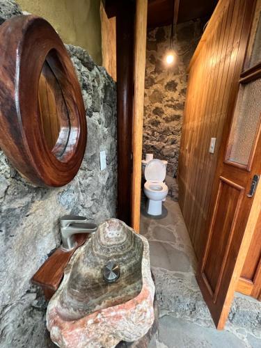 a stone bathroom with a toilet and a wooden door at Glamping en Casa Viento in Tepoztlán