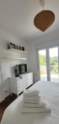a white bedroom with a bed with towels on it at Villa Pepe, casa compartida in Pontevedra