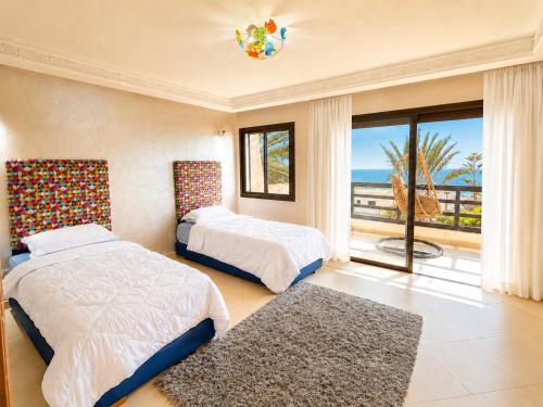 two beds in a bedroom with a view of the ocean at Villa Aglou Center in Zaouia Sidi Ouaggag