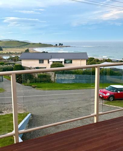 a balcony with a red car parked in front of a house at Ocean view on Semple in Kakanui