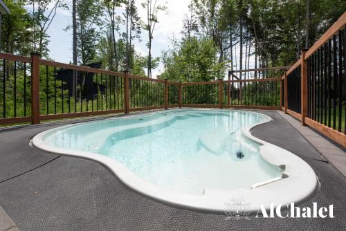 a hot tub in a deck with a fence at White Stag - Comfort & Serenity - Sauna & Pool in Pont-Rouge
