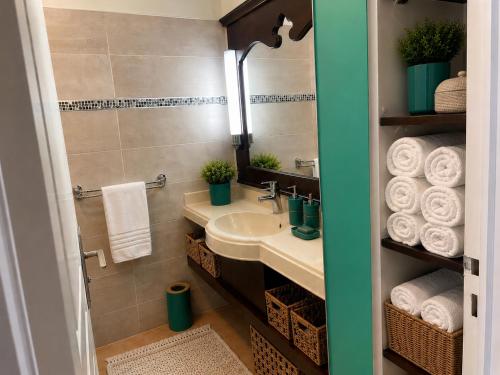 a bathroom with a sink and a mirror and towels at Couleur Caraïbes-TI EVASION appartement dan un village club 3 étoiles vue mer in Sainte-Luce