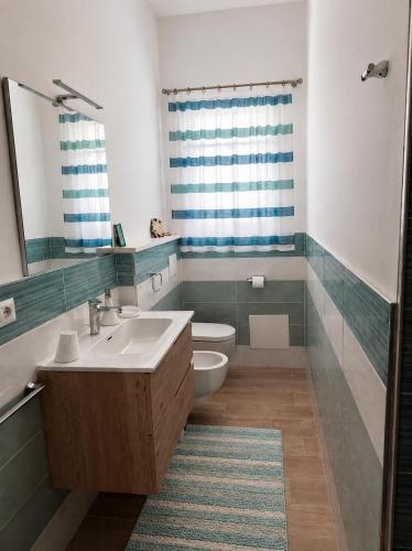 a bathroom with a sink and a toilet and a mirror at Brezza Marina & L'oasi Blu in Castelsardo