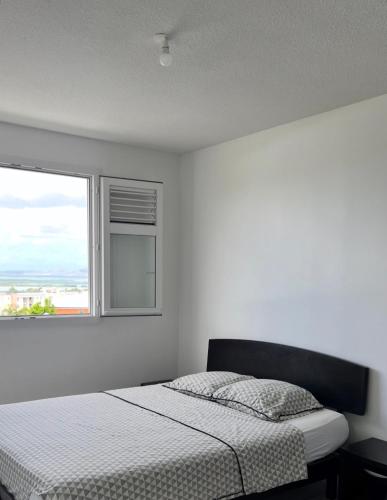 a white bedroom with a bed and a window at CHAMBRE Calme et Bien située in Le Lamentin